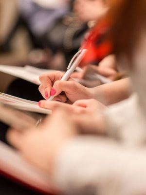 Close up of people taking notes during a conference