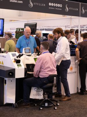 A group of people looking at machinery at a busy trade show booth.